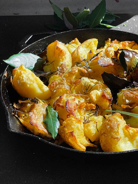 Roasted potatoes in a pan with bay leaves and rosemary
