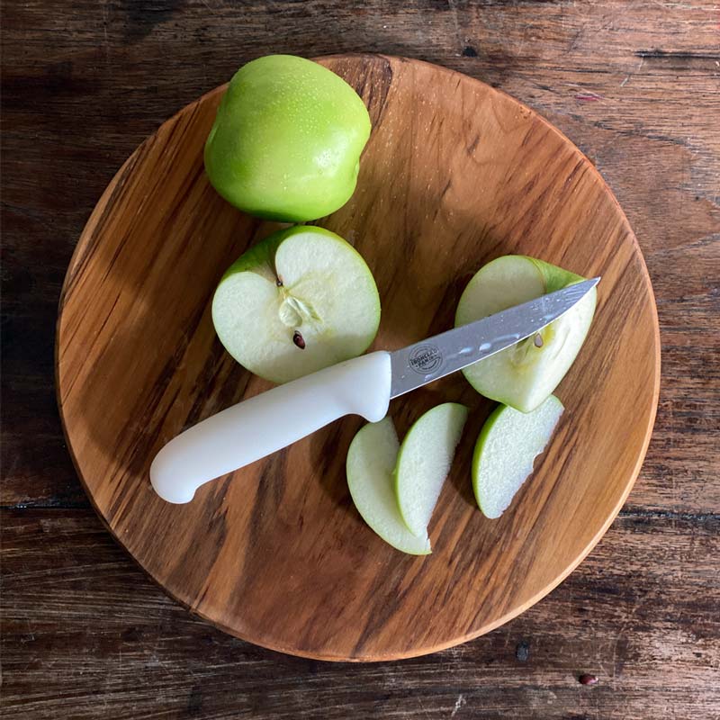 Paring knife on a chopping board with cut up granny smith apples 