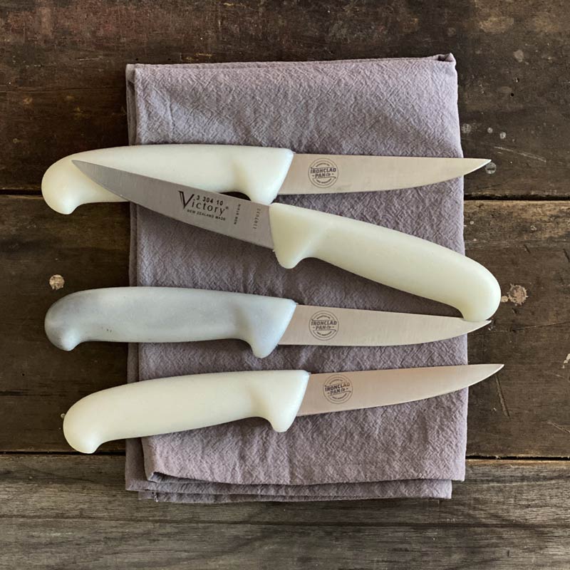 4 x paring knifes on a tea towel on wooden background