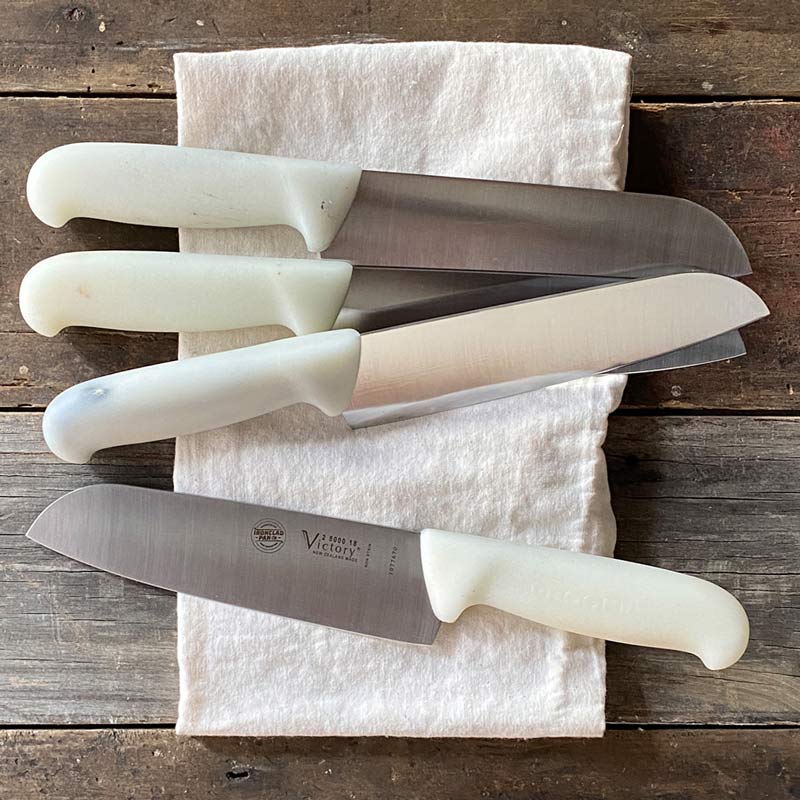 Group of Santoku knives on a tea towel on wooden background